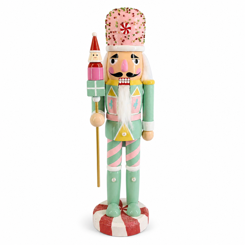 Pastel toy guard nutcracker figure in mint and pink, holding a gift staff with a Santa topper