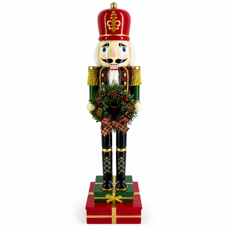 Plaid soldier nutcracker figure in red and green, holding a pine wreath and standing on gift boxes